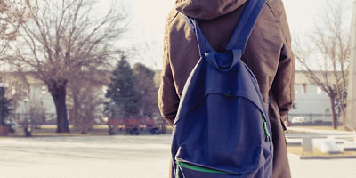 Person von hinten, die einen Rucksack trägt.