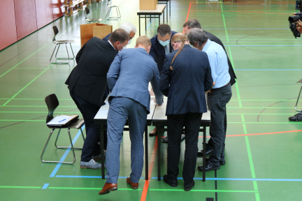 Mehrere Personen beugen sich über einen Tisch mit Stimmzetteln.