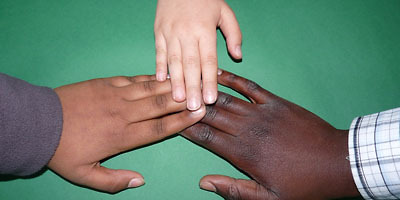 Hände von Menschen mit verschiedener Hautfarbe berühren sich.