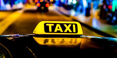 Ein beleuchtetes Taxi-Zeichen auf einem Autodach.
