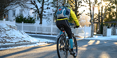 Eine Person fährt mit dem Fahrrad im Winter durch ein Wohngebiet.